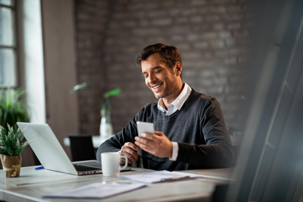 Qual o WhatsApp da Claro? Veja como entrar em contato 5 happy businessman texting mobile phone while working laptop office